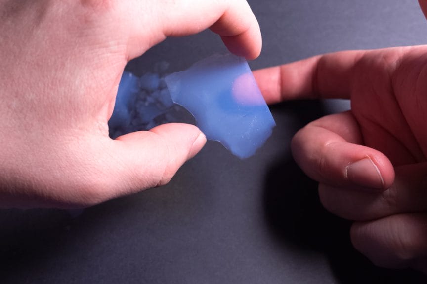 Human hands touching 'aerogel', which is a kind of synthetic material that comes from a gel