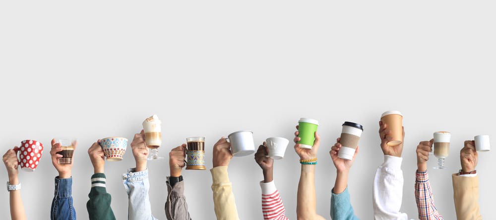 multicolored hands holding different coffee cups in the air