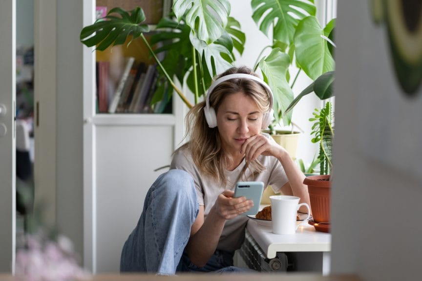 Woman sitting with headphones looking at book on her phone