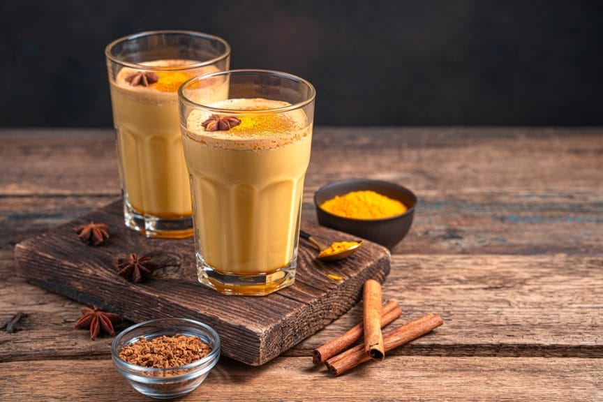 coffee alternative golden milk in two glasses with cinnamon and turmeric cloves