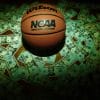 A basketball in money. College athletes are dealing with the pressure that comes with sports betting.