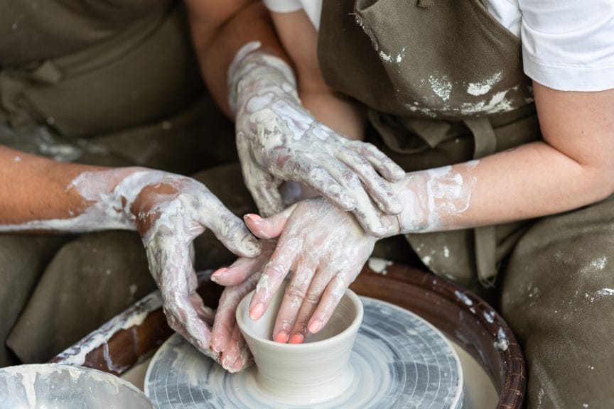 Romantic date making pottery. Man and woman in love doing clay jar together, holding hands. High quality photo