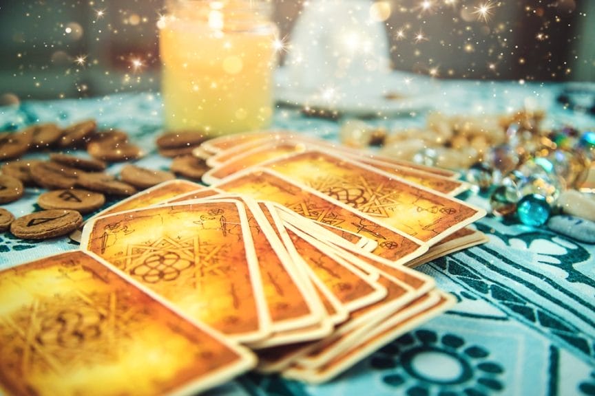 Tarot cards on a table surrounded by candles and stones.