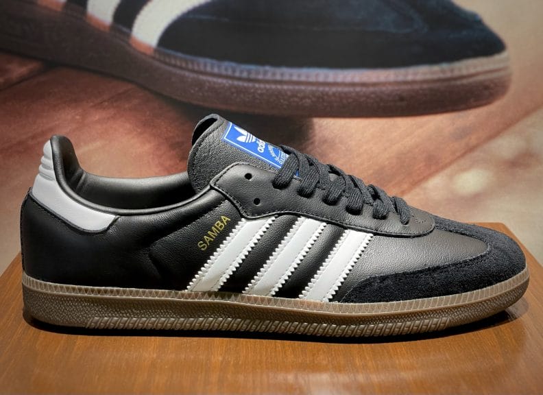 A black Adidas Samba OG shoe with black laces and a brown sole.