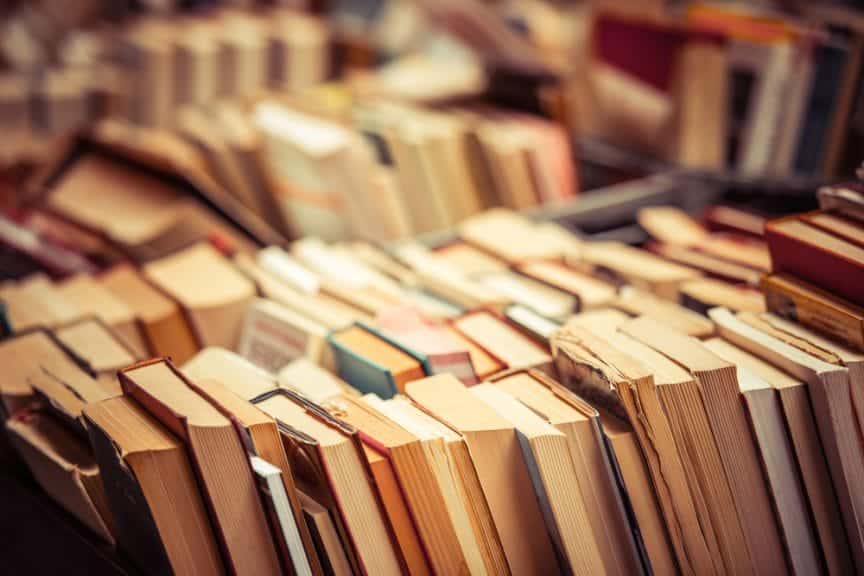 Lots of books laying upright in a cart