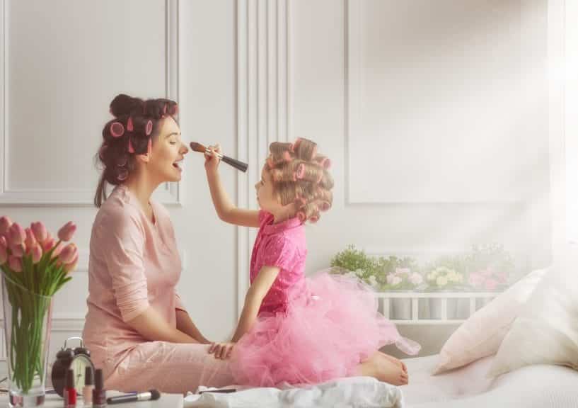 Young girl doing her mom's makeup.