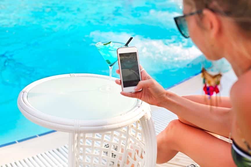 Woman taking photo of her martini by the pool