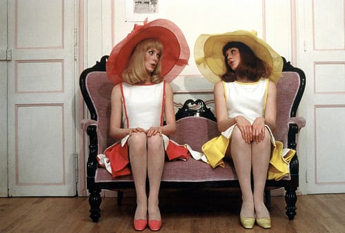 Delphine and Solange sit together in dreamy springtime outfits  as they sing the film's main theme.