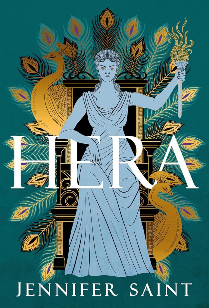 Image of book cover. Cover is a deep turquoise and dominated by a cartoon image of a woman sitting in a throne. The woman is a pale blue illustration, wearing a toga and holding up a fiery torch in her left hand, she is wearing a stern expression. Her throne is black but gilded with gold details and surrounding her throne are peacock feathers and two peacocks. In front of her is the title "Hera" in white writing. Below the woman is the author's name, Jennifer Saint, also in white writing