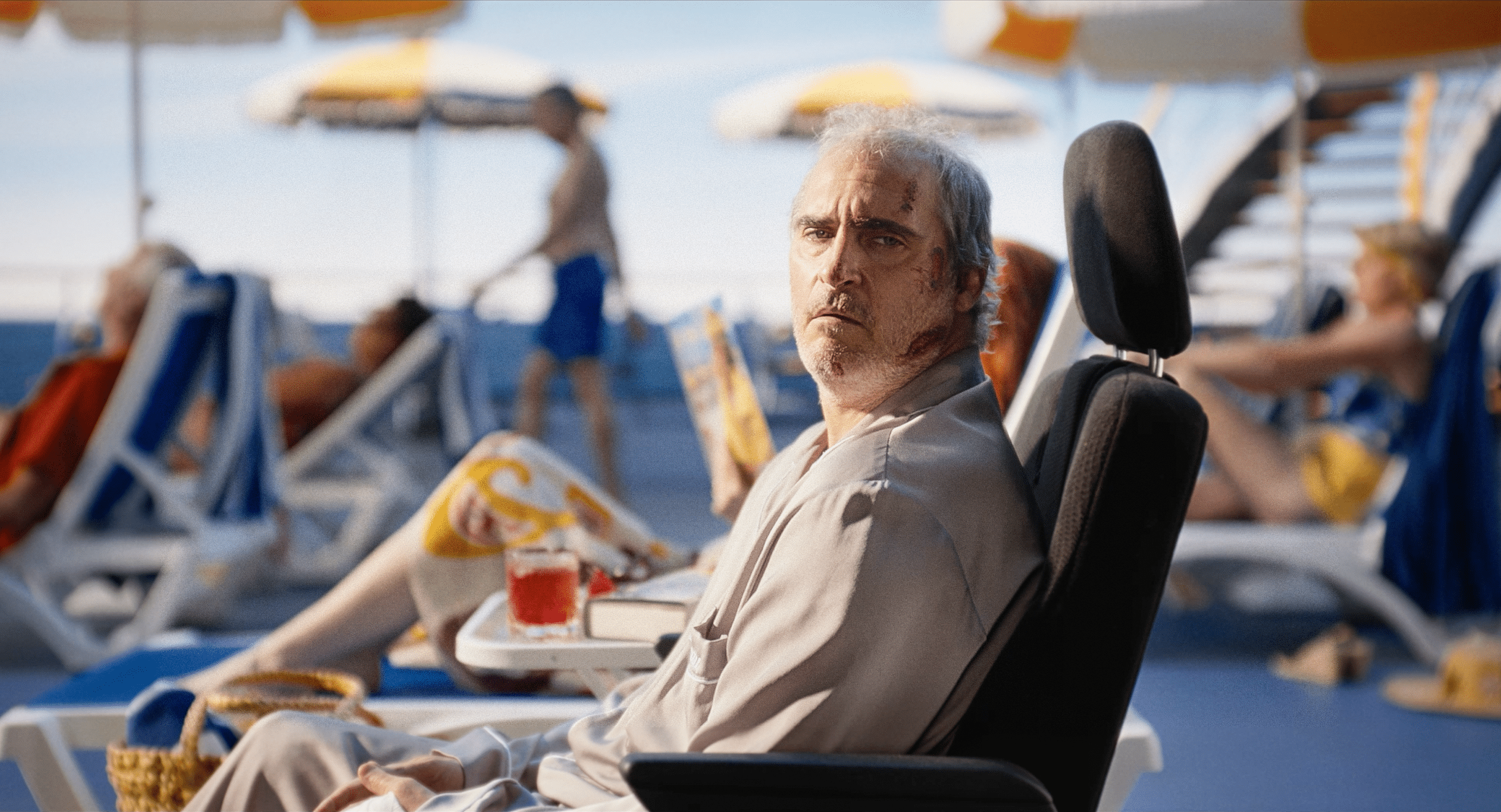 A man is sitting in a chair looking confused, bleeding from his head. He is in a vacation resort. He is unhappy, and his name is Beau.
