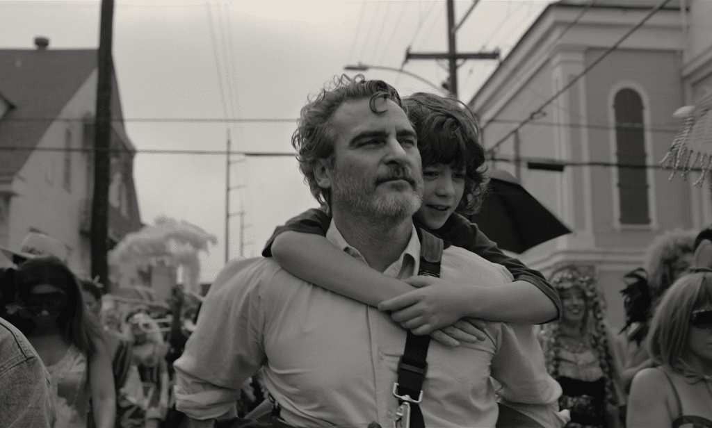 A man an his nephew are strolling around in a parade, the screen is black and white.