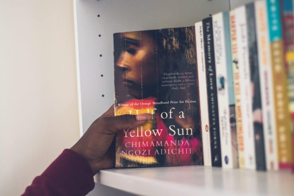 A hand taking a book from a shelf as part of a literary community.