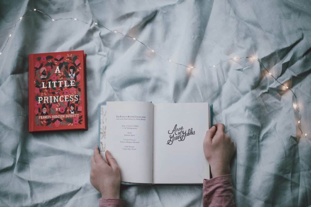 An opened book next to a different book that is closed, as part of a literary community.