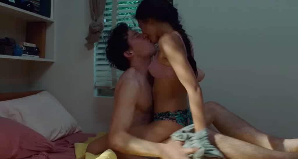 A man and woman, half-naked, kissing on a bed.