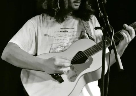 Jay from Crywank playing the guitar in a black and white image