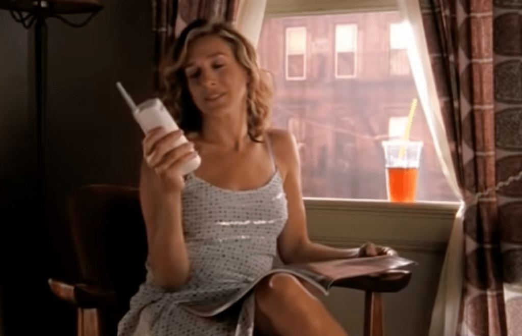 Carrie Bradshaw, the main character of the show Sex and the City takes a phone call in her apartment while reading a magazine.
