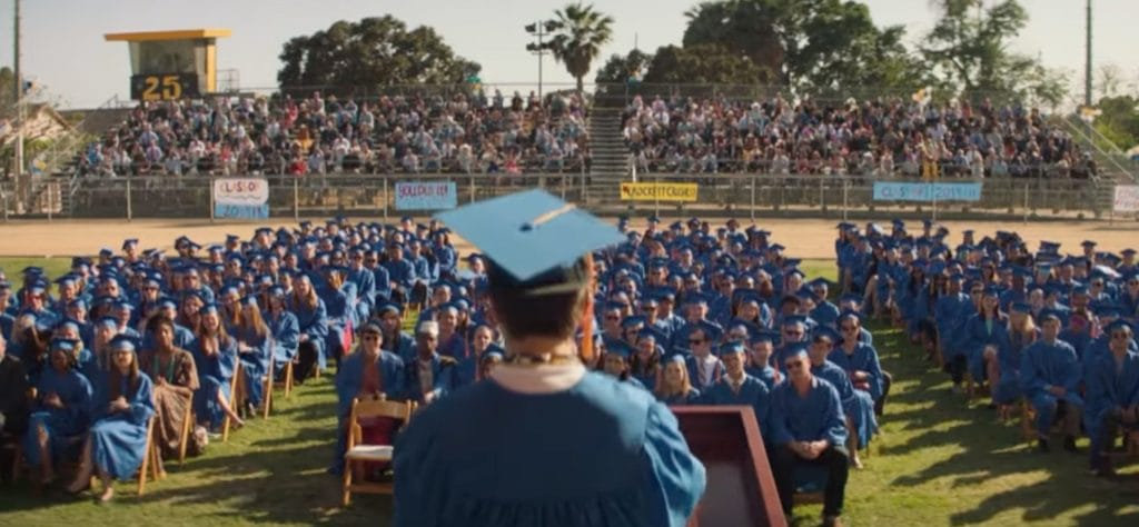 An image of the graduating class in Booksmart. We are looking at the crowd from the perspective of the student behind the podium.