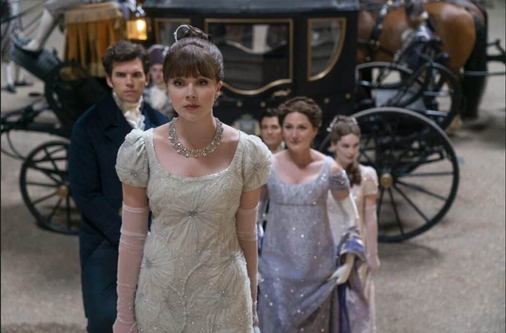 Eloise Bridgerton walking out of her carriage with her family trailing behind.