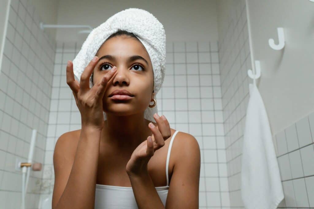 Young woman doing skin care to prioritize self care.
