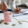 woman putting coins in a piggy bank