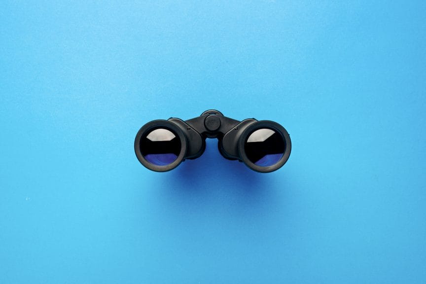 Binoculars on a light blue background.