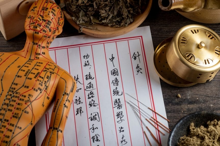 Acupuncture needles, mannequin, and Chinese chart