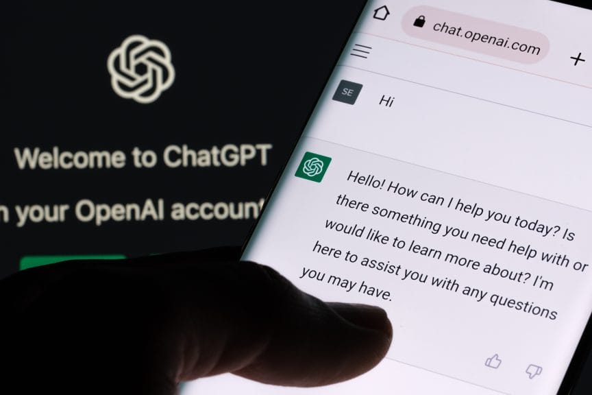 ChatGPT screen seen on smartphone and laptop display with ChatGPT login screen in the background.