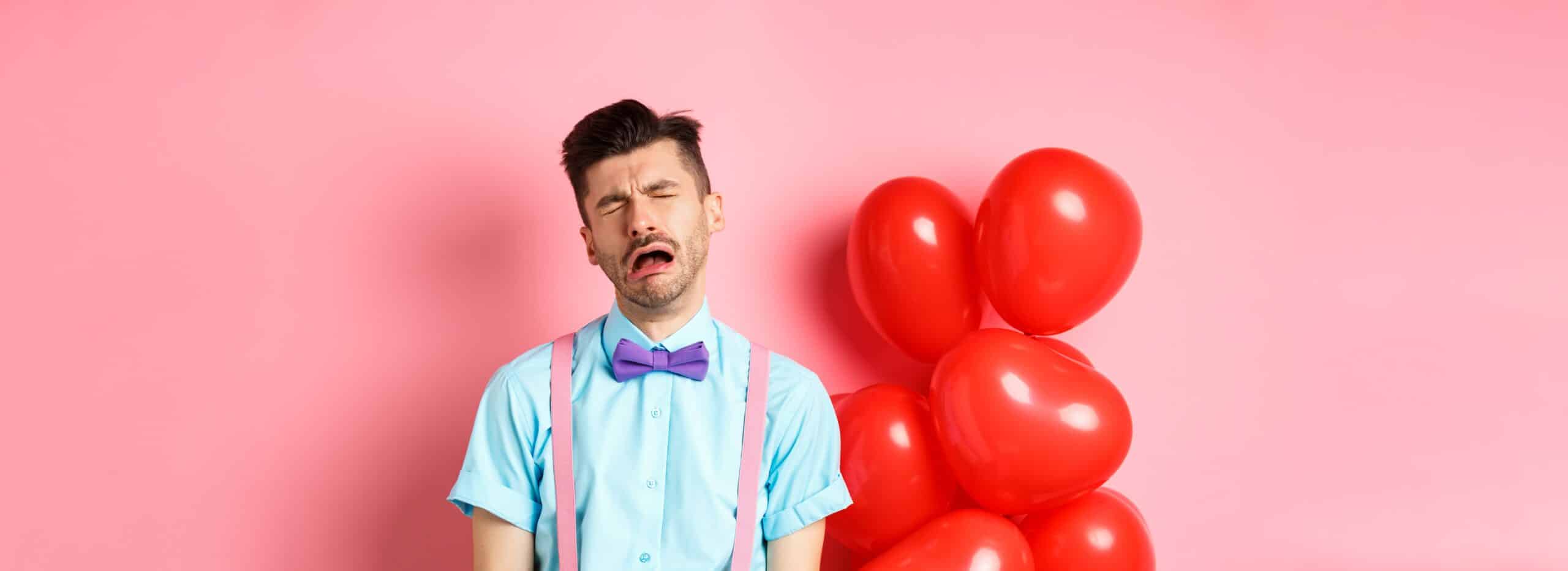 Man crying in front of pink wall