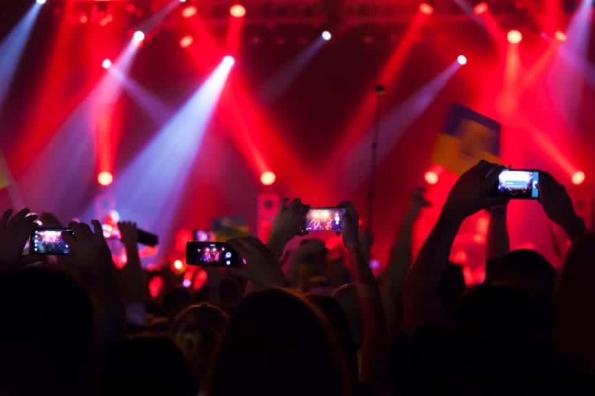 People at concert recording a video or photo with red lights.