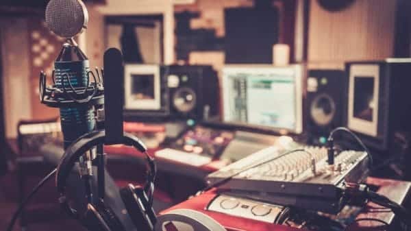 Close-up of boutique recording studio control desk with headset, microphone, and computers