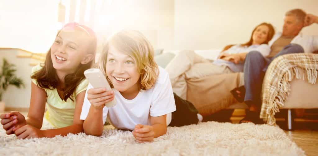 Siblings lying on the floor watching tv together