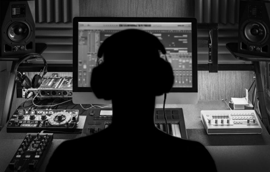 A man producing electronic music in a project home recording studio. Silhouette. Black and white image.