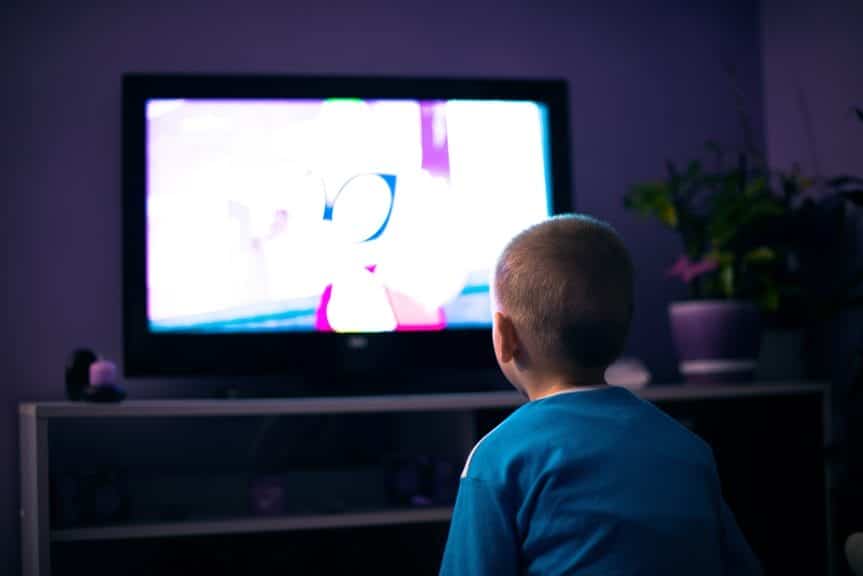 A Child sitting in the living room watching Cartoons.
