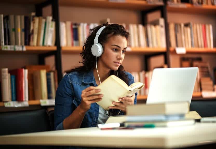 Girl with headphones studying in a library