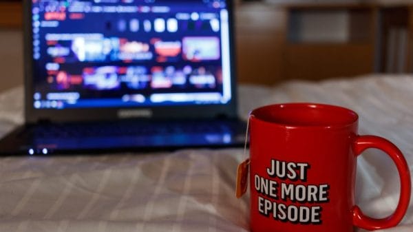 Laptop screening Netflix with mug stating "just one more episode"