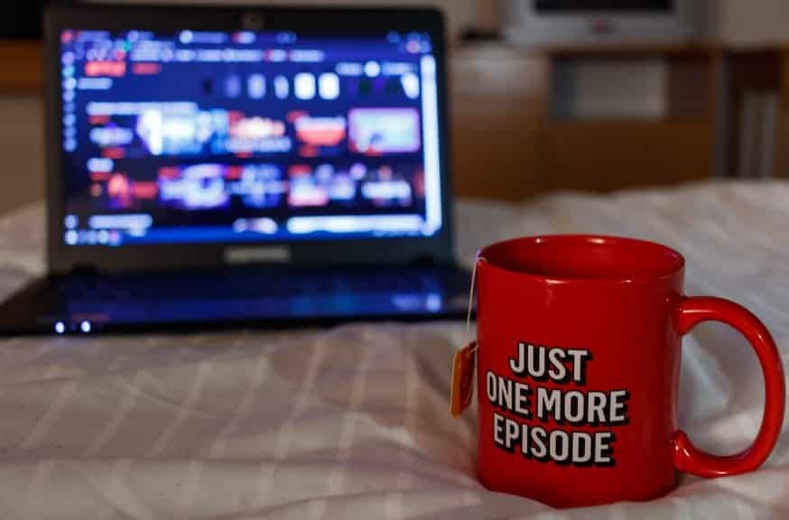 Laptop screening Netflix with mug stating "just one more episode"