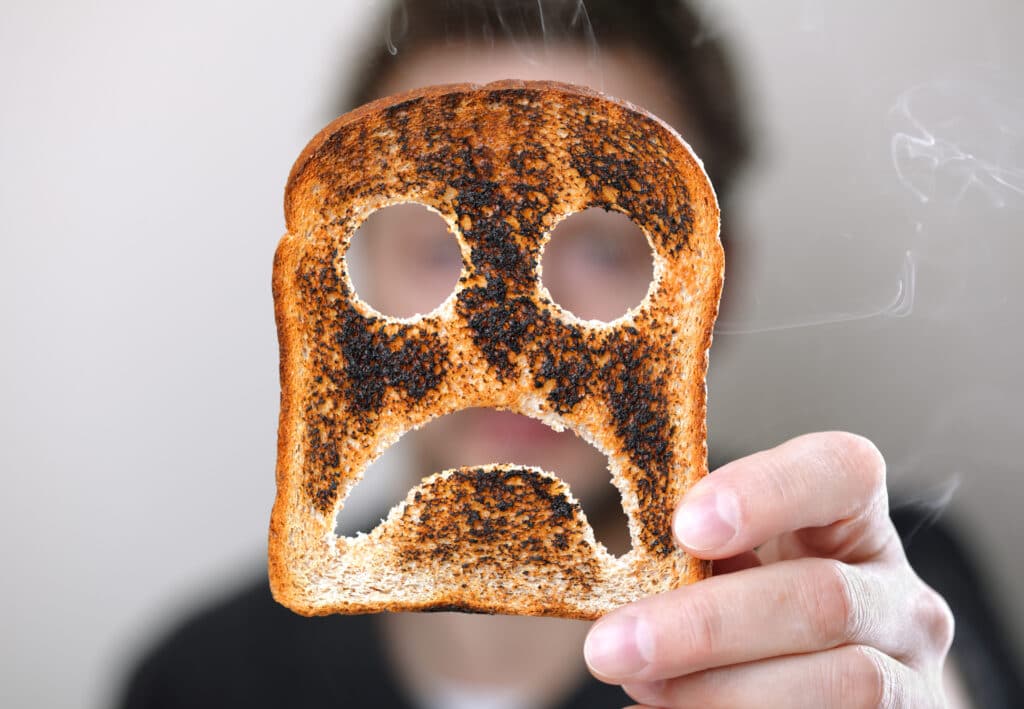 Man holding burnt toast with a sad face
