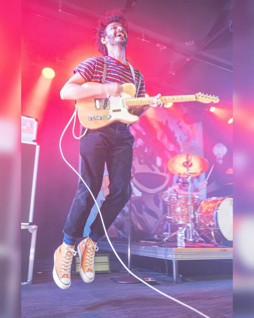 A guitar player leaping in their performance.