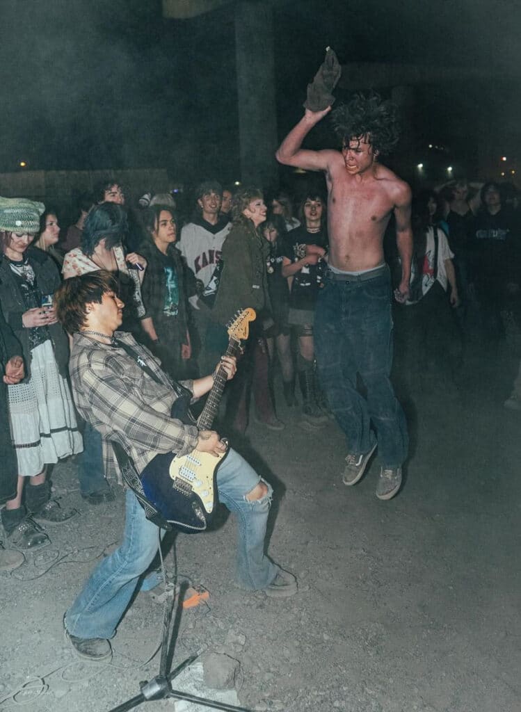 A guitar player and dancer at a punk show.