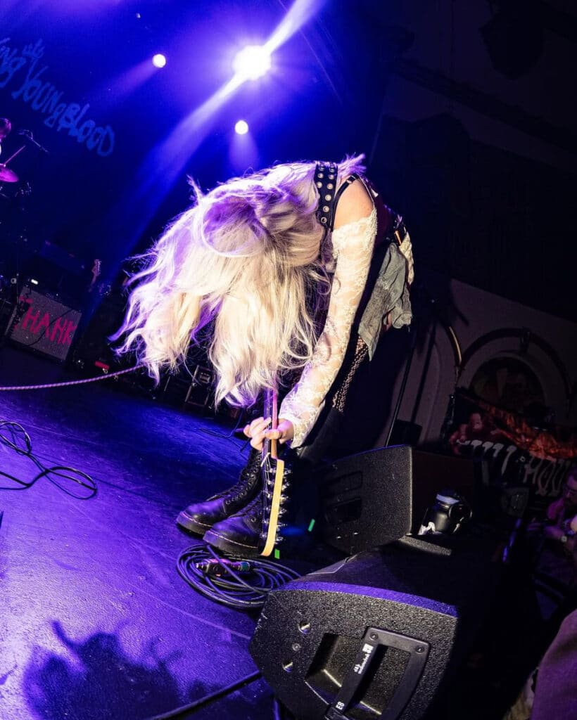A guitar players rocking out in front of a crowd.
