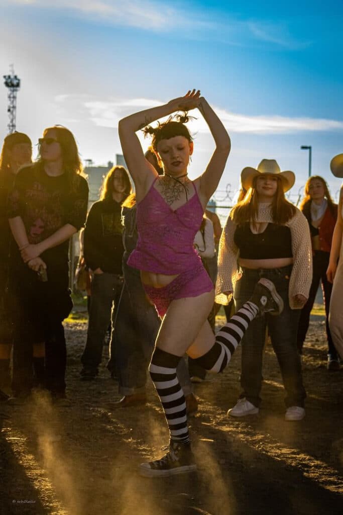 A person dressed in a lacy two piece and white and black striped knee high socks mid dance.