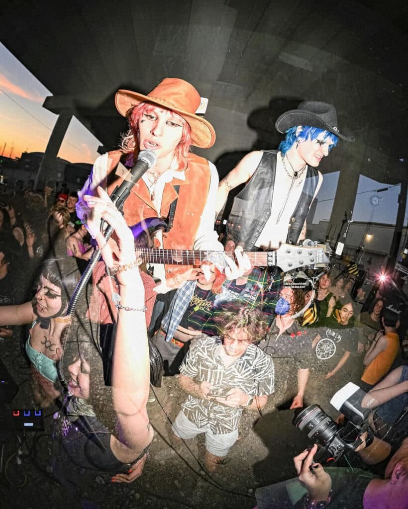 A double exposure captured photo of the band Catica performing to a crowd under a bridge in Seattle.