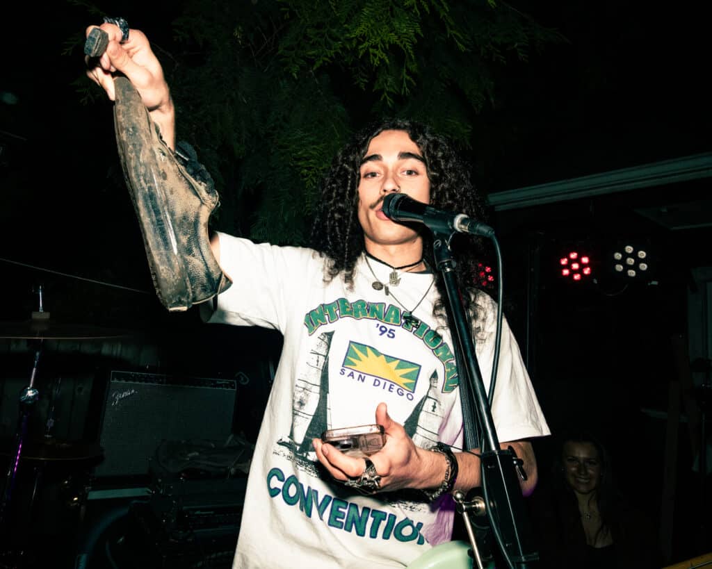 A band member holds a dirty shoe and a pair of keys recovered from the mosh pit of a punk show.