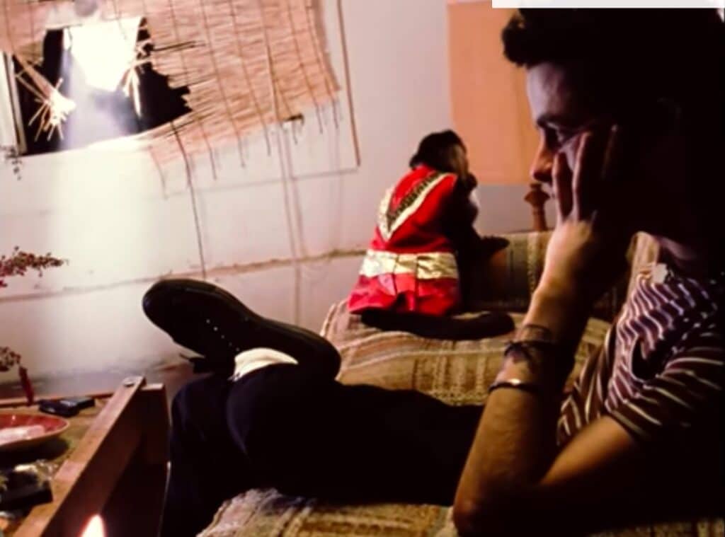 Billie Joe Armstrong is sitting on a couch with a small monkey behind him.