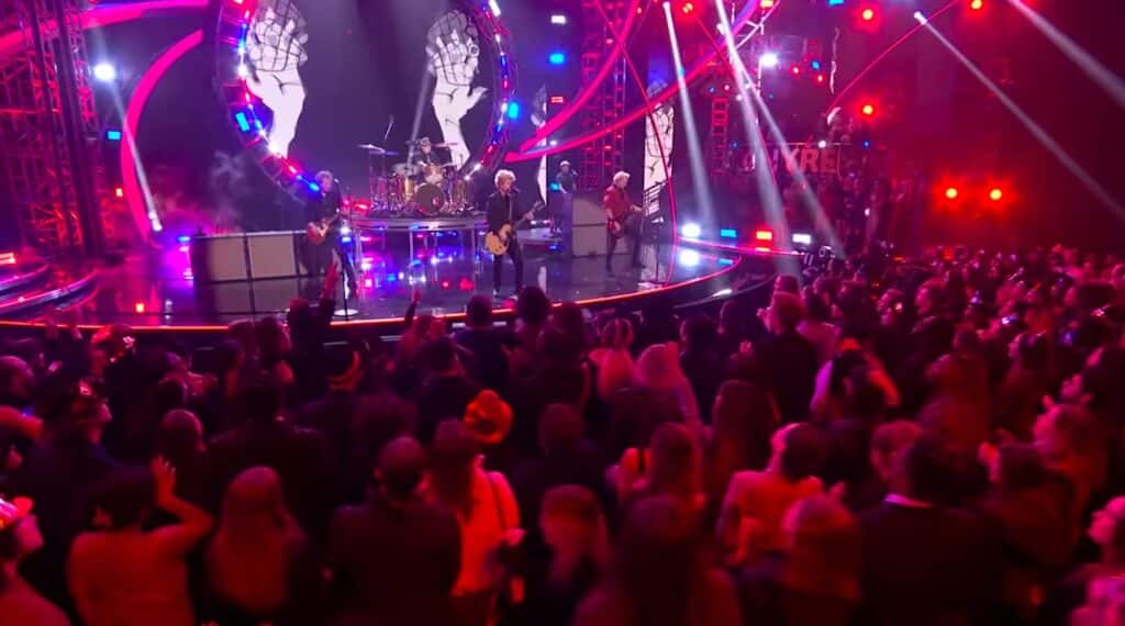 Green day is performing in front of a crowd.