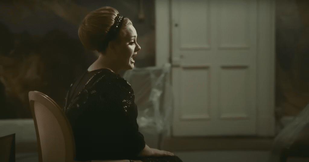 Adele in her music video for "Rolling in the Deep." She is sitting and singing in front of a white door.