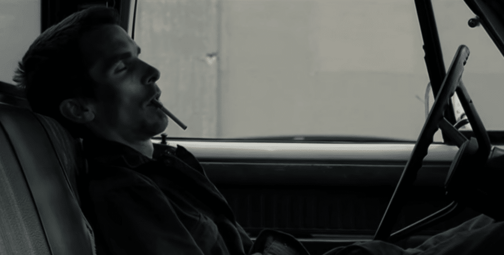 A man is sitting in the car smoking a cigarette.