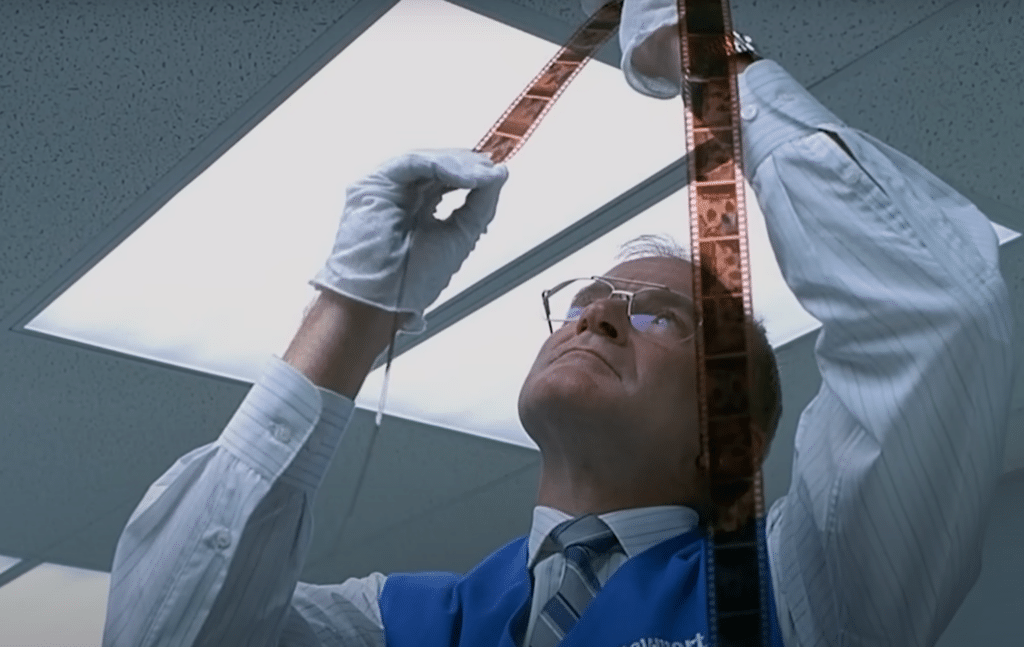 The photo technician is checking the film he has developed.