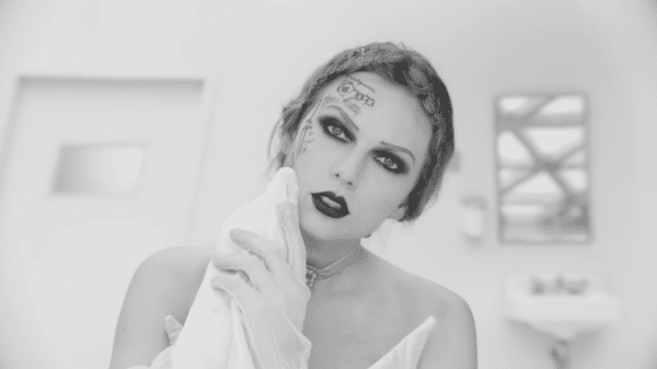 Taylor Swift in black and white in the music video for "Fortnight." She is seen wiping her face and revealing tattoos.