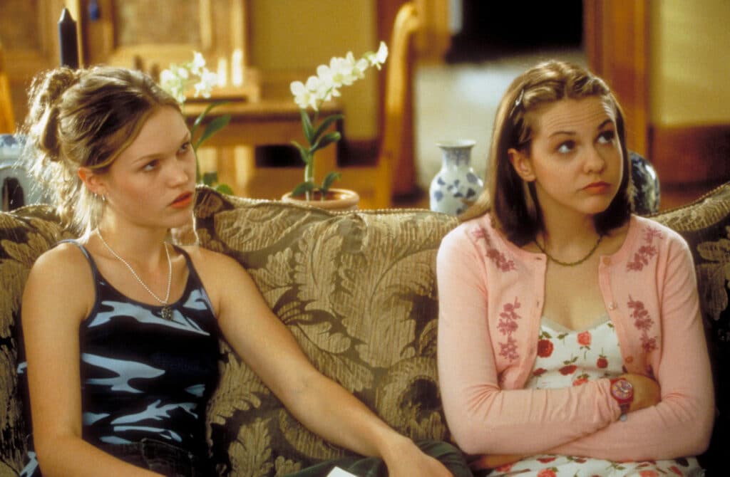 Kat (Julia Stiles) and Bianca (Larisa Oleynik) sit together, being berated by their father (Larry Miller) - not shown.